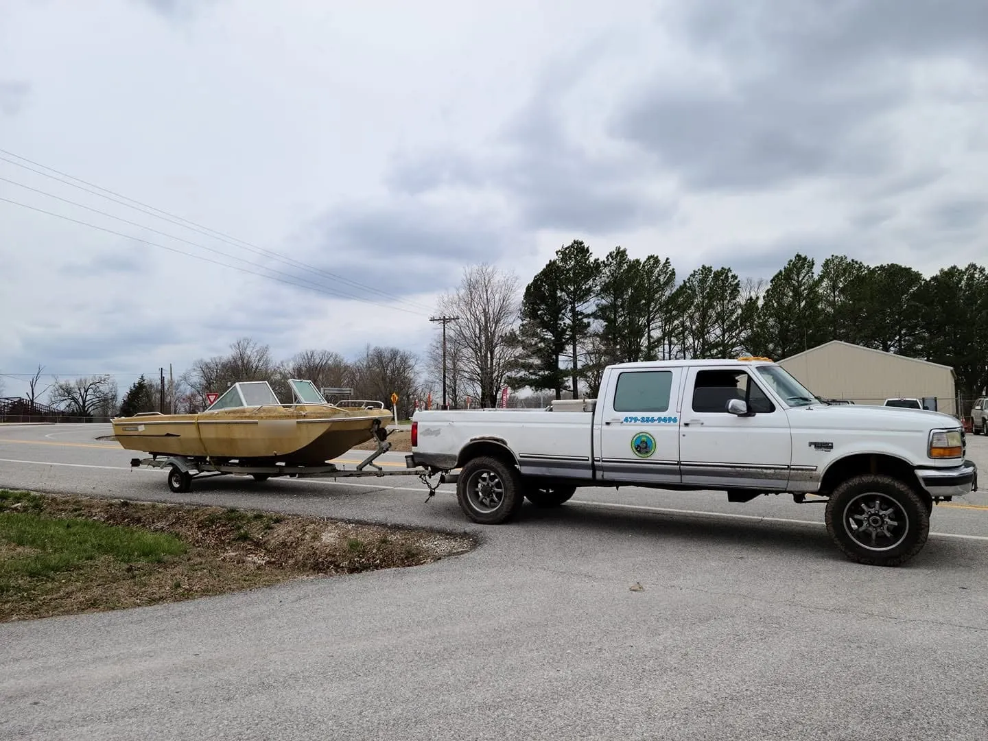 Chums Junk Removal hauling away an old boat on its trailer behind the Chums truck