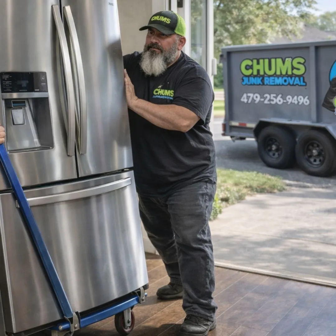 A Chums Junk Removal crew member moving a stainless refrigerator to the branded trailer during an appliance removal