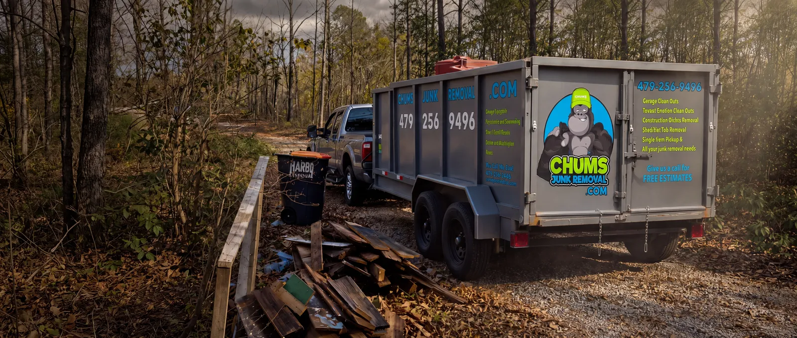 The Chums Junk Removal truck and 16-foot dump trailer, branded with the gorilla logo, in the Northwest Arkansas woods